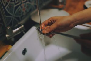 Man washing fork in sink